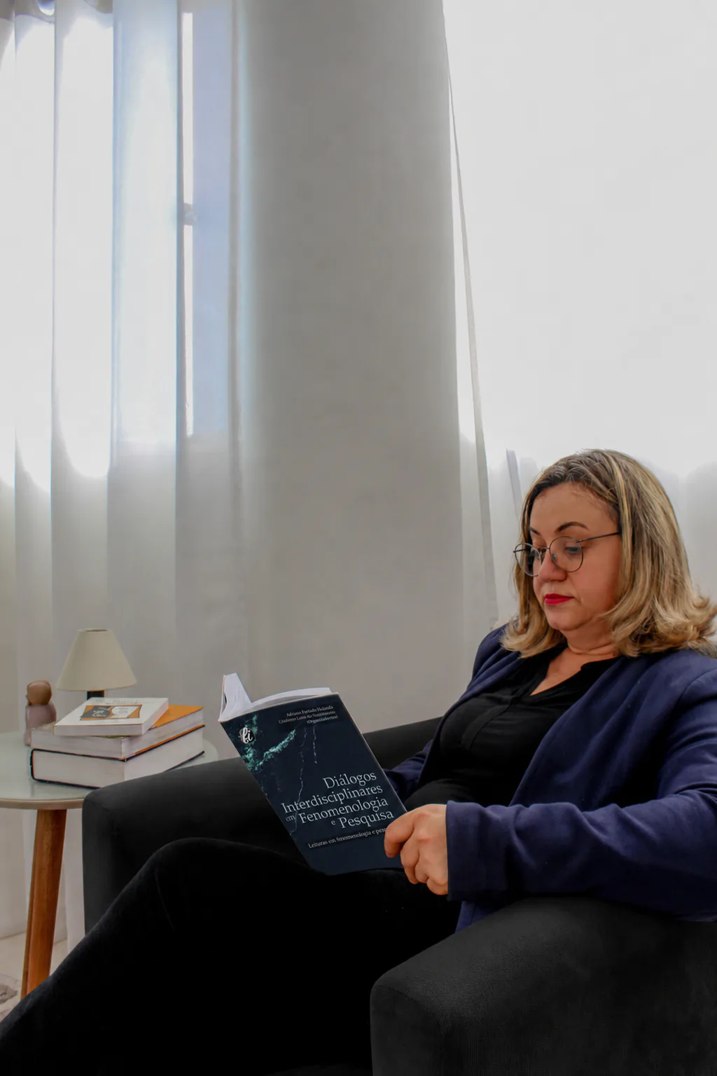 Geni Aparecida Vieira Mello lendo uma obra sobre Fenomenologia e Pesquisa